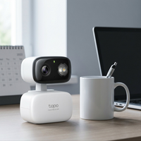 Product image of the Tapo C216 camera on a desk, next to a coffee mug for scale reference.